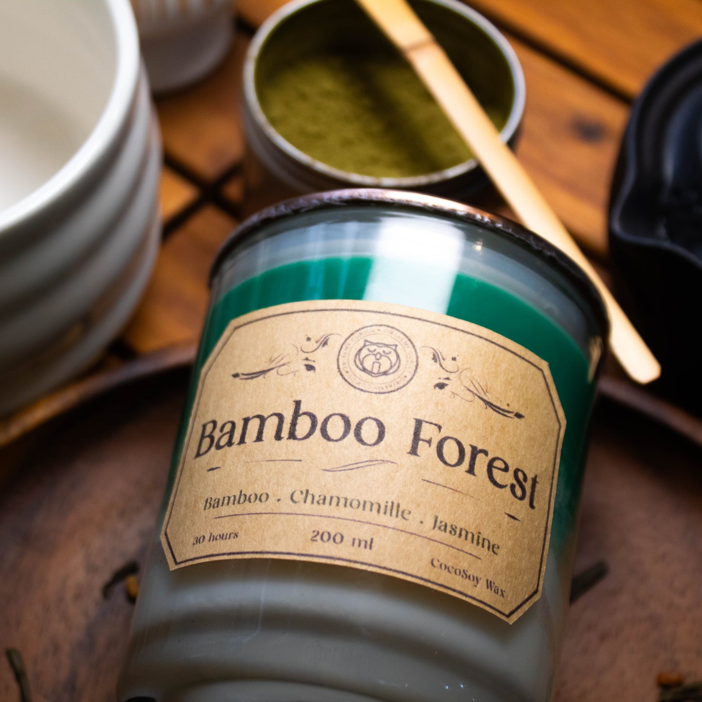 Bamboo Forest candle with a label on a wooden surface with other candles and containers.