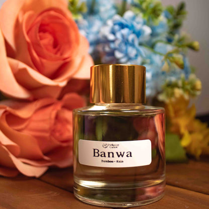 Bottle of Banwa reed diffuser with flowers in the background