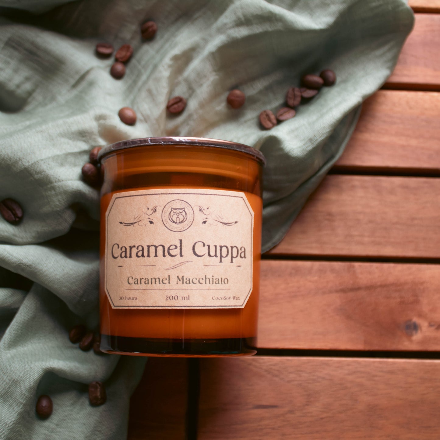 Caramel Cuppa candle on a wooden surface with coffee beans