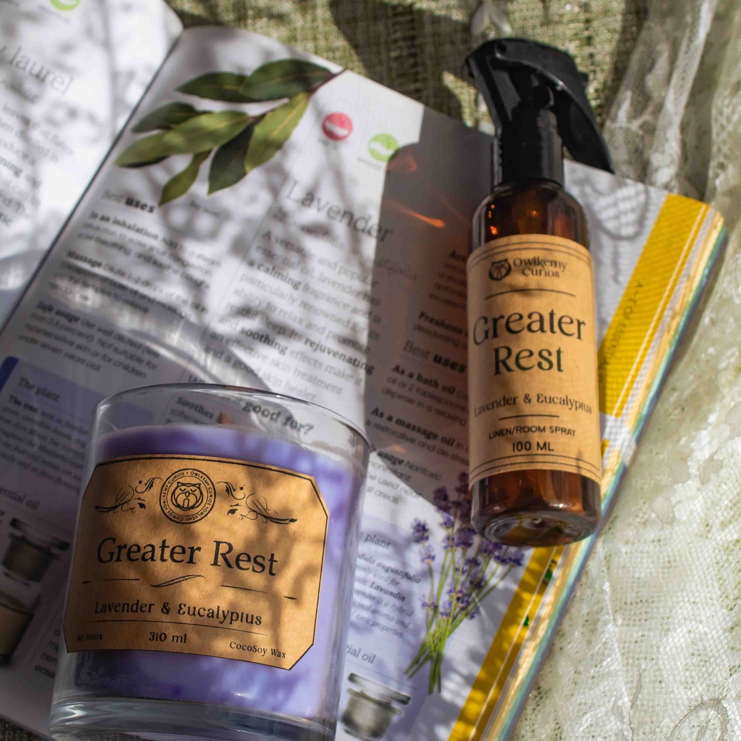 Greater Rest candle and spray bottle on a textured surface with a magazine underneath