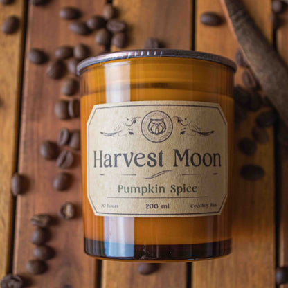 Harvest Moon Pumpkin Spice candle on a wooden surface with coffee beans