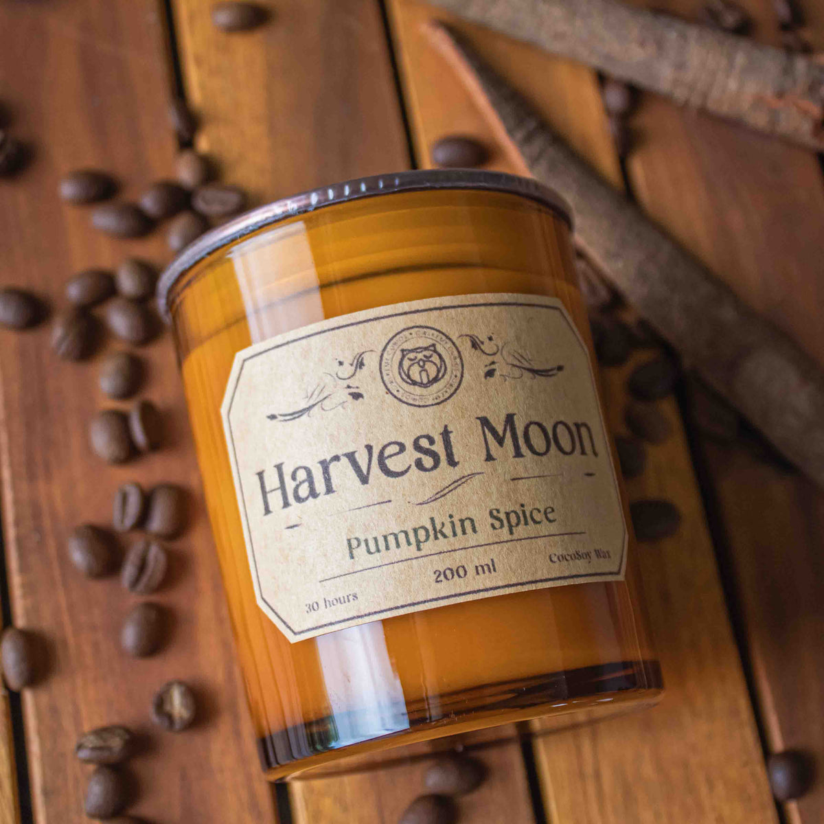 Harvest Moon Pumpkin Spice candle on a wooden surface with coffee beans