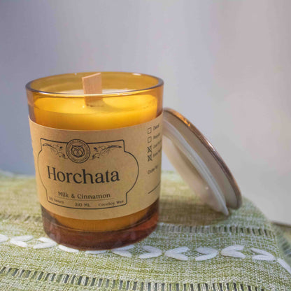Candle labeled 'Horchata' on a green textured surface with a blurred background