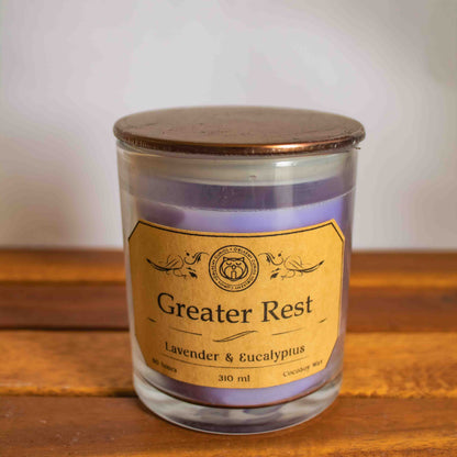 Candle jar labeled 'Greater Rest' with lavender and eucalyptus on a wooden surface.