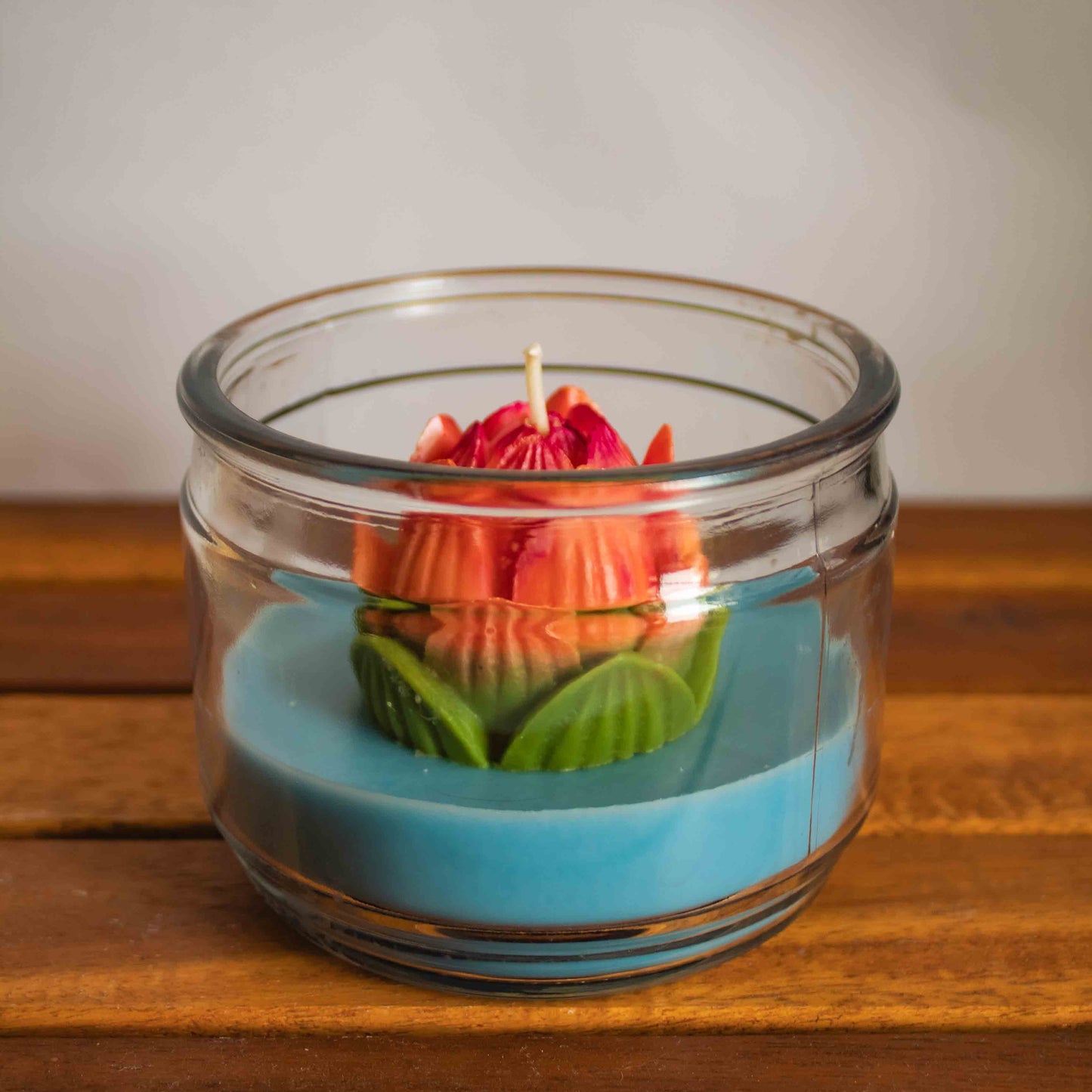 Candle in a glass jar with a floral design on a wooden surface