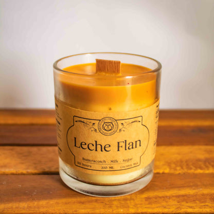 Leche Flan candle in a glass jar on a wooden surface with a white background