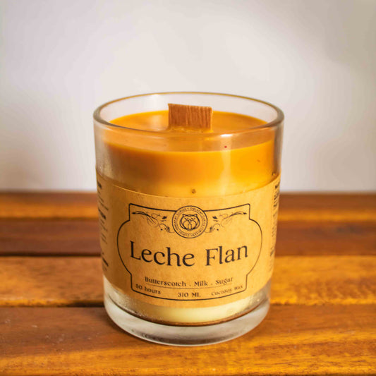 Leche Flan candle in a glass jar on a wooden surface with a white background