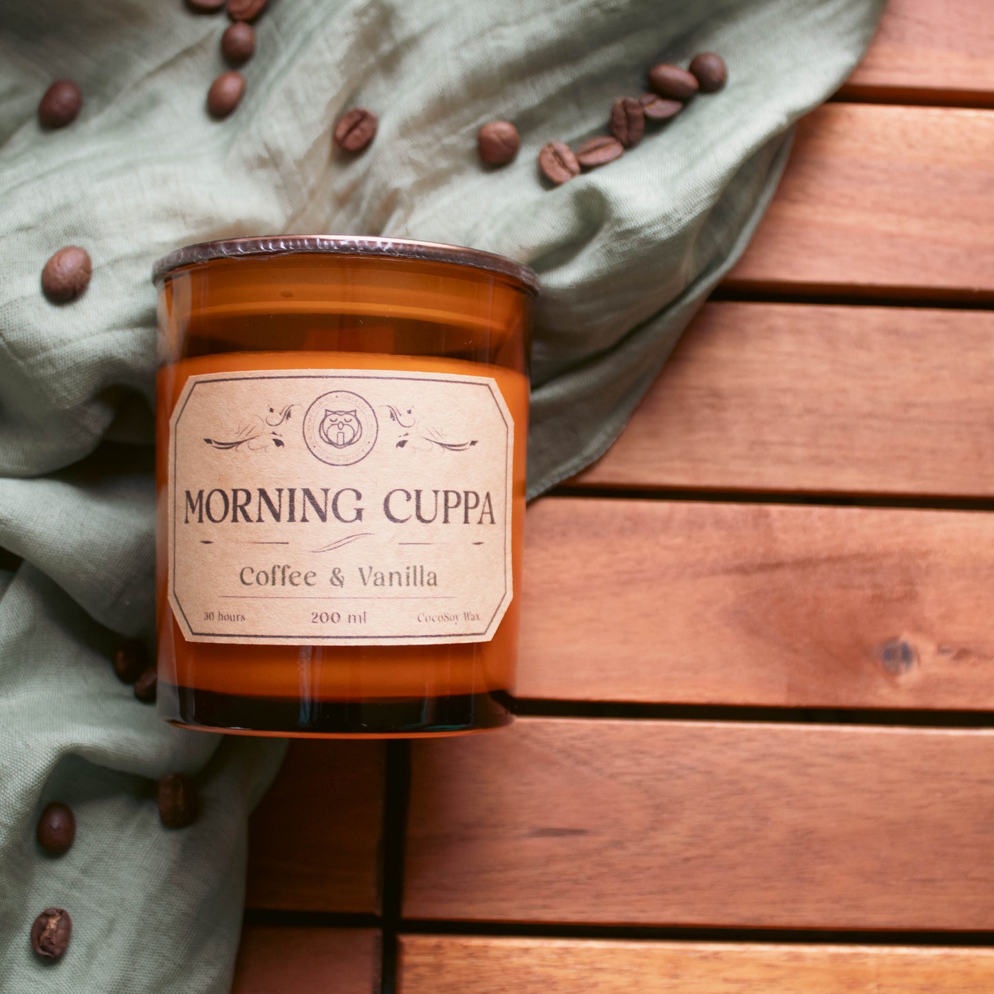 Candle labeled 'Morning Cuppa' on a wooden surface with coffee beans.
