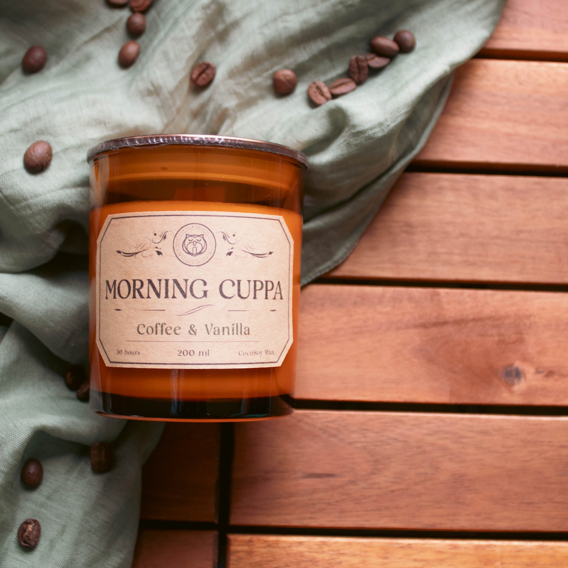 Candle labeled 'Morning Cuppa' on a wooden surface with coffee beans.