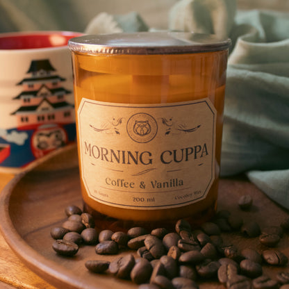 Jar of 'Morning Cuppa' coffee and vanilla with a mug and coffee beans on a wooden surface.