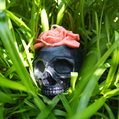 Black skull with a pink rose in green grass