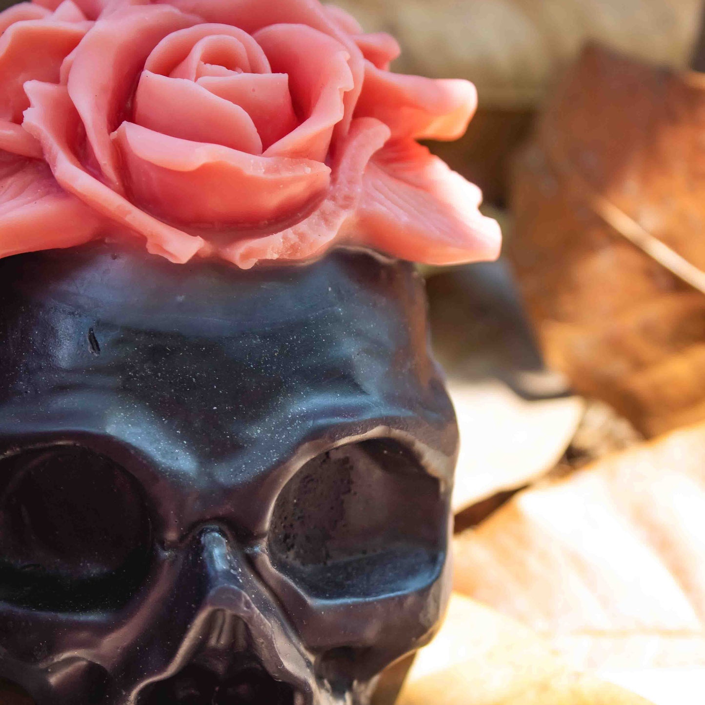 Black skull with a pink flower on a blurred natural background