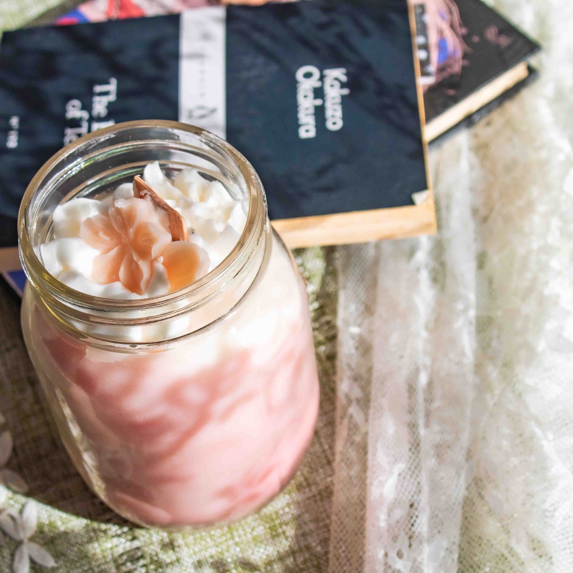 Mason jar with a pink drink and wooden stick on a textured surface with books in the background