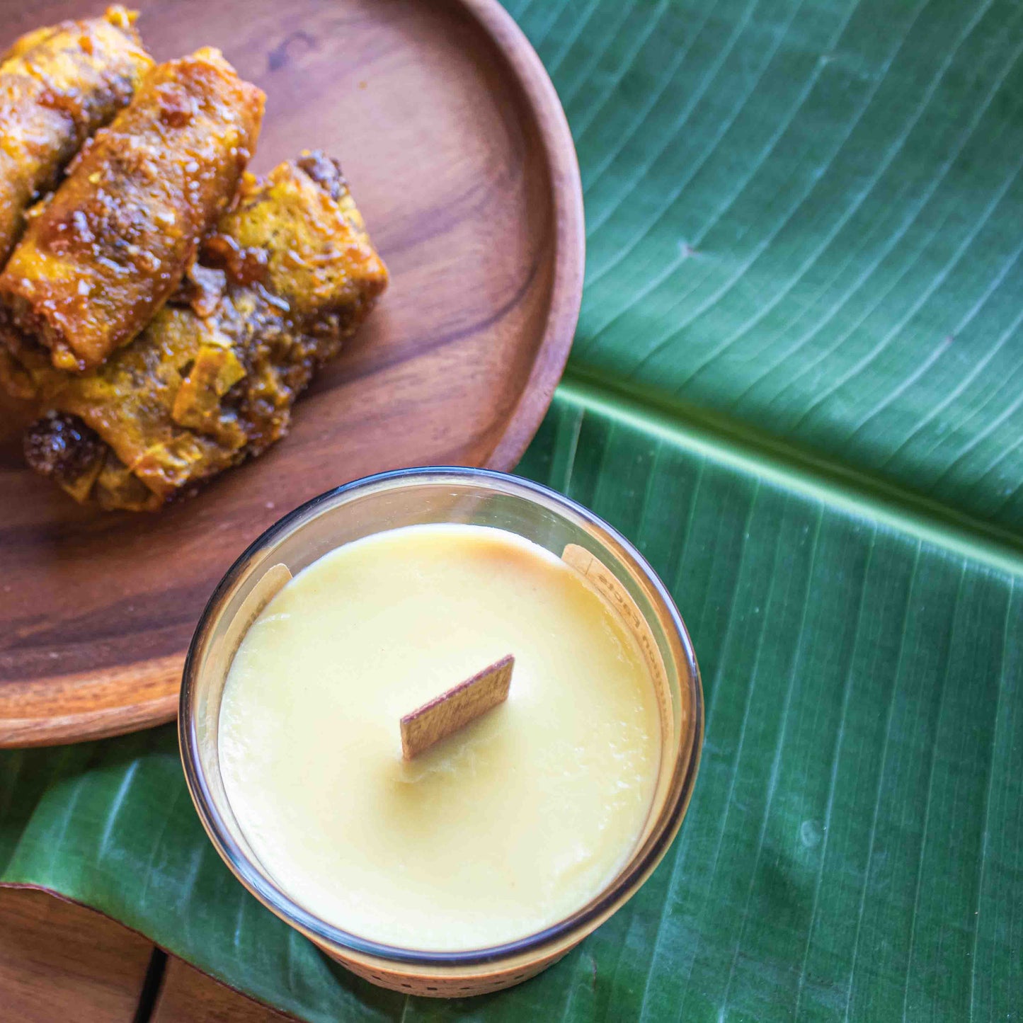 Wooden plate with fried food on a green leaf, next to a small candle